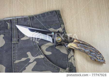 Knife on camouflage background. 77747928