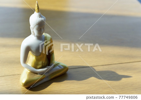 Small buddhist statue on wooden table Small buddhist statue on wooden table 77749806