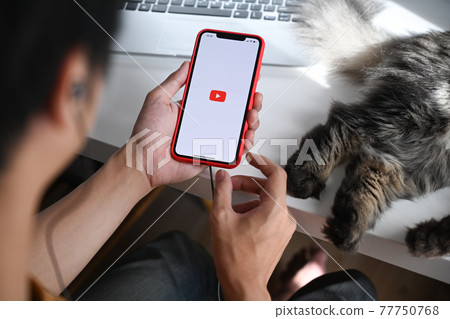 Chiang Mai, Thailand - May 13, 2021 : Man holding iPhone 11 Pro Max with Youtube app. Youtube is the popular online video sharing website. Chiang Mai, Thailand - May 13, 2021 : Man holding iPhone 11 Pro Max with Youtube app. Youtube is the popular online video sharing website. 77750768