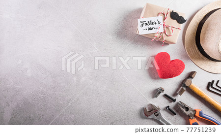 Happy Father's Day decoration including; beautiful tie with mustache, hand tools, gift box , red heart and hat on dark stone background. 77751239
