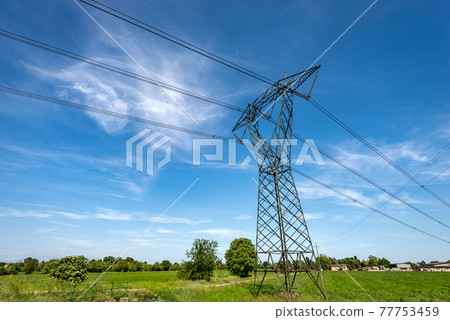 High voltage tower - Power Line in Countryside against a Blue Sky with Clouds High voltage tower - Power Line in Countryside against a Blue Sky with Clouds 77753459