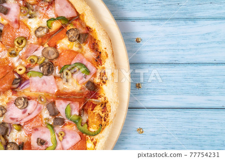 Delicious large pizza with veal and mushrooms on a blue wooden background Delicious large pizza with veal and mushrooms on a blue wooden background 77754231