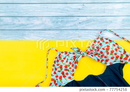 Top view of the swimsuit lying on a blue wooden and yellow background.Summer vacation concept 77754258