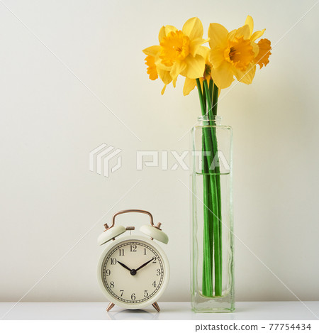 Alarm clock and flowers in vase on white background 77754434