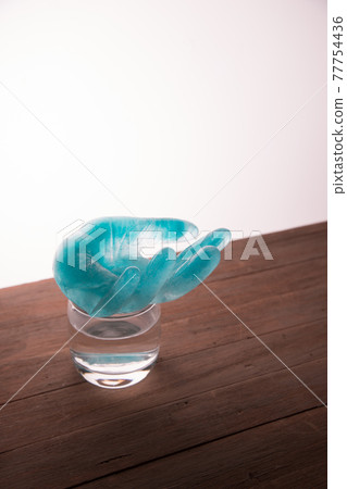 Frozen water with a blue dye in the shape of a human hand on a glass of water. The concept. Copy space 77754436