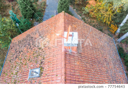 Inspection of the red tiled roof of a single-family house, inspection of the condition of the tiles on the roof of a detached house 77754643