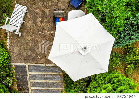 Vertical aerial photograph of a bright parasol on a terrace, taken from close up with the drone. Vertical aerial photograph of a bright parasol on a terrace, taken from close up with the drone. 77754644