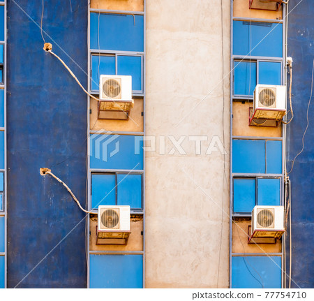 Detailed view of a blue skyscraper with the air conditioning fans behind the windows 77754710