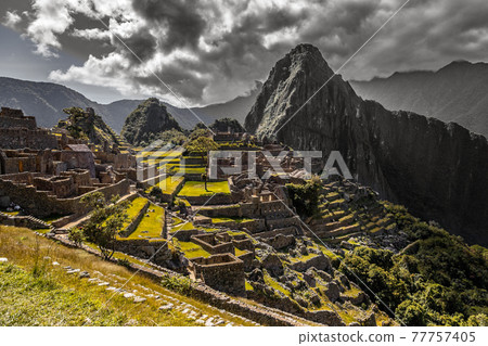 Panoramic view to old Inca ruins and Wayna Picchu with grey clou Panoramic view to old Inca ruins and Wayna Picchu with grey clou 77757405
