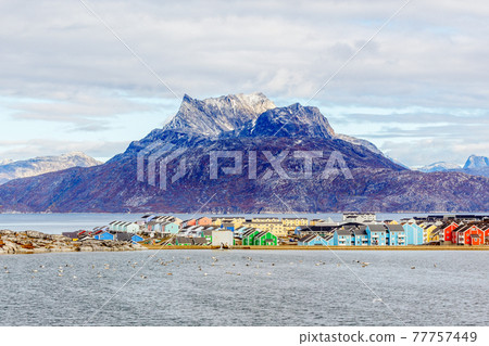 Colorful Inuit buildings in residential district of Nuuk city with lake in the foreground and snow peak of Sermitsiaq mountain, Greenland 77757449