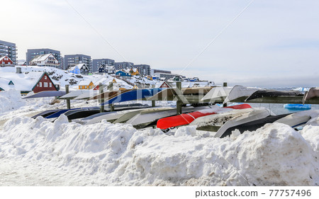 Inuit kayaks stored for a winter time in snow with Modern buildings and small cottages in the background, Nuuk old city harbor, Greenland Inuit kayaks stored for a winter time in snow with Modern buildings and small cottages in the background, Nuuk old city harbor, Greenland 77757496