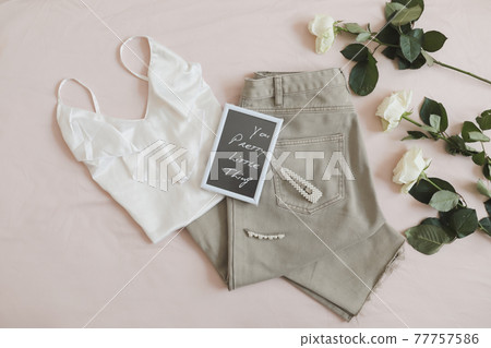 Overhead view of woman's casual spring summer outfit. Jeans, sandals, accessories and flowers on beige background. Flat lay, top view. Overhead view of woman's casual spring summer outfit. Jeans, sandals, accessories and flowers on beige background. Flat lay, top view. 77757586