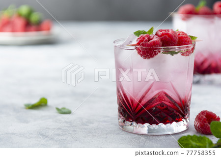 Raspberry cold drink cocktail with mint leaf and ice cubes. Summer fresh beverage in glass. Copy space. Raspberry cold drink cocktail with mint leaf and ice cubes. Summer fresh beverage in glass. Copy space. 77758355