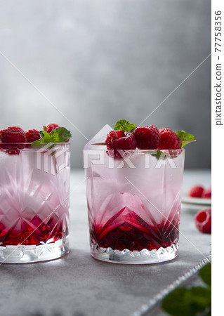 Raspberry cold drink cocktail with mint leaf and ice cubes. Summer fresh beverage in glass. 77758356