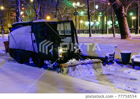Communal car clears snow in the park. 77758554