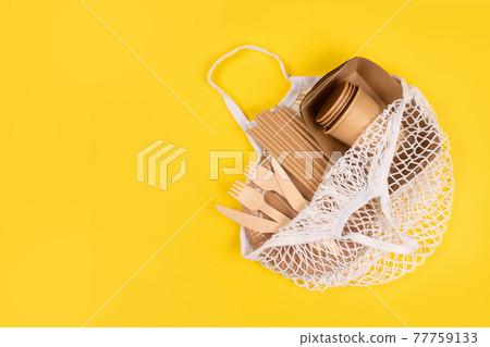 Kraft paper food cups and containers with wooden cutlery in cotton net bag on yellow background with copy space, eco-friendly tableware . Street food take away paper packaging, selective focus 77759133