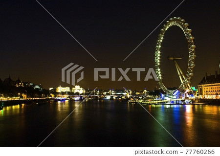 London cityscape with the London Eye lit up over the Thames at night 77760266