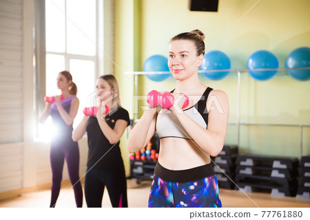 Fitness, sports, training, gym and lifestyle concept - a group of women working with steppers in the 77761880