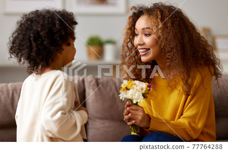 Cute little son giving flower bouquet his mom for Mothers day Cute little son giving flower bouquet his mom for Mothers day 77764288
