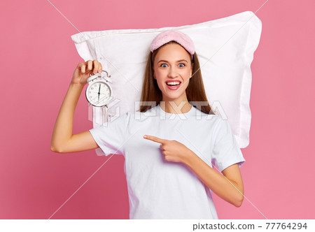 Excited female demonstrating alarm clock 77764294