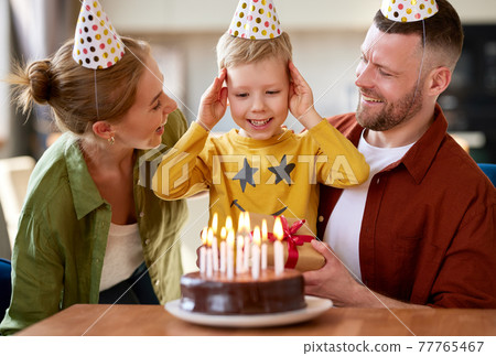 Portrait of happy child boy celebrating birthday with young parents at home 77765467