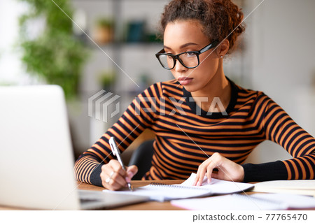 Young afro american woman working remotely or studying online at home Young afro american woman working remotely or studying online at home 77765470