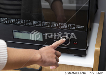 Hands of a housewife who uses a microwave 77766604