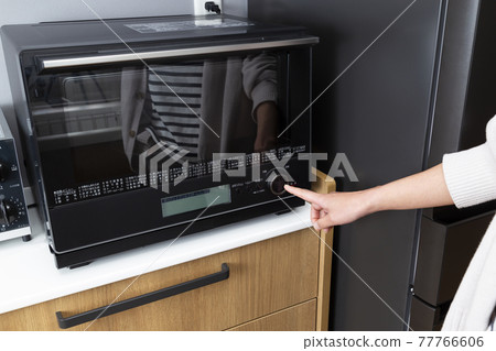 Hands of a housewife who uses a microwave 77766606