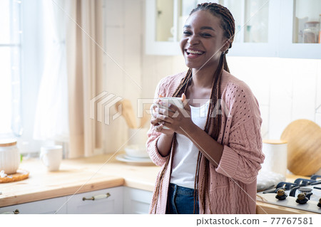 Domestic Relax. Portrait Of Cheerful Black Woman Drinking Coffee In Kitchen Interior 77767581