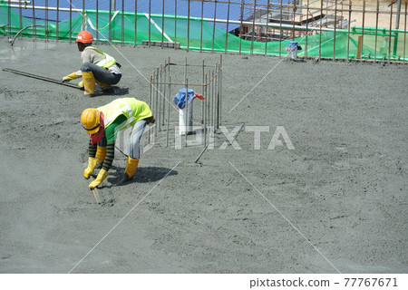 MALACCA, MALAYSIA -JANUARY 18, 2017: Construction workers leveling  wet concrete that poured on floor at the construction site. They are using special tools made from wood.  77767671