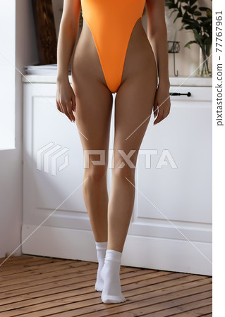 Crop seductive woman in bodysuit standing provocatively in light room Crop seductive woman in bodysuit standing provocatively in light room 77767961