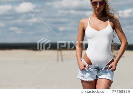 Sexy woman in white swimsuit holding shirts Sexy woman in white swimsuit holding shirts 77768559