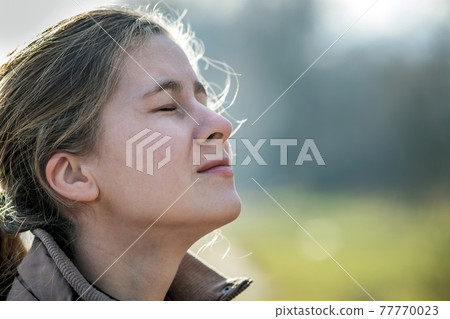 Portrait of young attractive woman enjoying warm sunny day in early spring outdoors. 77770023