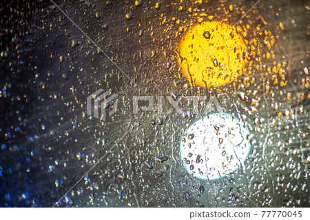 Abstract colorful background of glass surface with water drops and blurred city lights. 77770045