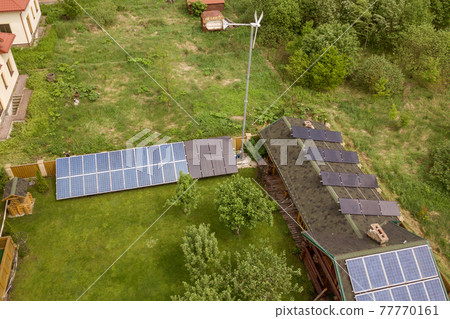 Aerial view of a barn with solar panels on roof and wind generator turbine. 77770161