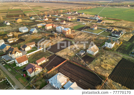 Aerial landscape of small town or village with rows of residential homes and green trees. Aerial landscape of small town or village with rows of residential homes and green trees. 77770170