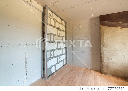Unfinished brick wall in a room under construction prepared for drywall plates frame installation. Unfinished brick wall in a room under construction prepared for drywall plates frame installation. 77770211