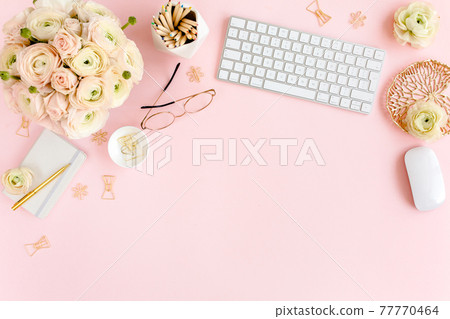 Stylized, pink women's home office desk. Workspace with computer, bouquet ranunculus and roses, clipboard on pink background. Flat lay. Top view. 77770464
