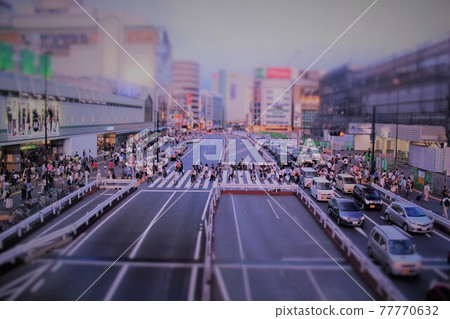 Miniature urban scenery: A diorama-style representation of a train station intersection and people passing by at dusk. Miniature urban scenery: A diorama-style representation of a train station intersection and people passing by at dusk. 77770632