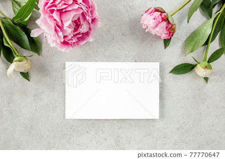 Mockup invitation, blank paper greeting card and peonies on gray stone table. Flower background. Flat lay, top view. 77770647