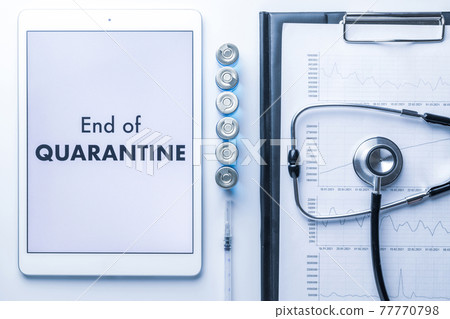 End of covid. Medical equipment: doctor stethoscope, hospital healthcare charts, syringe with needle and white tablet with text on screen. End of quarantine concept. 77770798