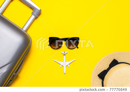 Hello summer. Womens accessories traveler: suitcase, white plane, sunglasses on yellow background with empty space for text. Tranquil beach scene with copy space. 77770849