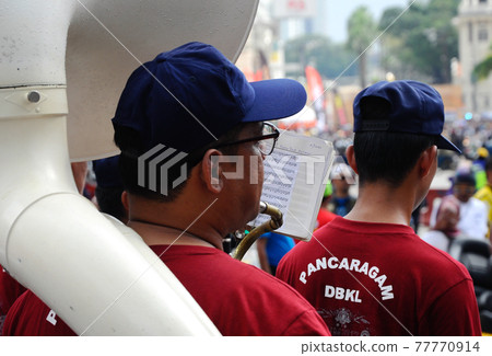 KUALA LUMPUR, MALAYSIA -FEBRUARY 22, 2017: Brass band player is playing a musical instrument while guided by musical notes. 77770914