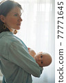 Mother with baby standing at home 77771645