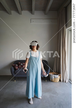 Woman in VR glasses experiencing virtual reality at home Woman in VR glasses experiencing virtual reality at home 77771647
