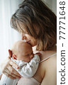 Mother kissing baby tenderly in forehead 77771648