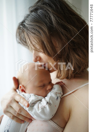 Mother kissing baby tenderly in forehead Mother kissing baby tenderly in forehead 77771648