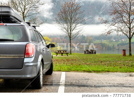 A car with roof baggage trunk parked on the side of the street on a parking lot in mountains. 77771738