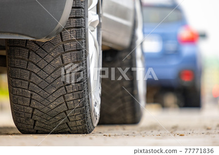 Closeup of parked car on a city street side with new winter rubber tires. Closeup of parked car on a city street side with new winter rubber tires. 77771836