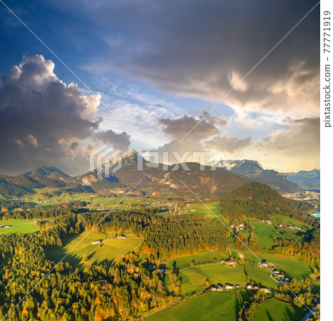 Aerial view of green meadows with villages and forest in austrian Alps mountains. 77771919